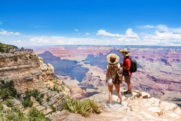 Couple on top of the mountain, looking at beautiful summer mountain  landscape. Friends on hiking trip enjoying view of Colorado river. South Rim. Grand Canyon National Park, Arizona, USA.