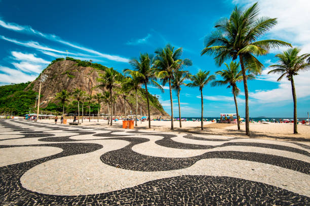 Rio de Janeiro, Brazil - January 27, 2017: Famous mosaic of sidewalk in Copacabana beach, palm trees and the Leme mountain.